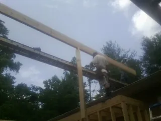 Carpenter setting a ridge beam over a new addition frame — Ice Dam Removal by Roofing Brothers in Williamsburg